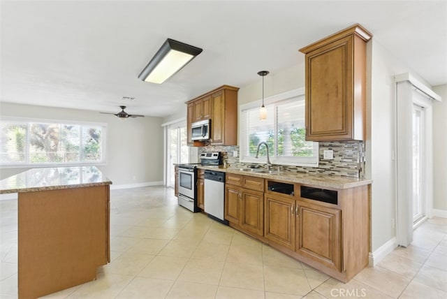 56620 Hidden Gold Dr, Yucca Valley, CA 92284 - kitchen featuring appliances with stainless steel finishes, backsplash, brown cabinetry, ceiling fan, and light stone countertops