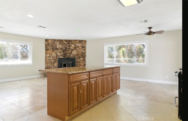 56620 Hidden Gold Dr, Yucca Valley, CA 92284 - kitchen with light tile patterned floors, baseboards, light stone countertops, a center island, and ceiling fan
