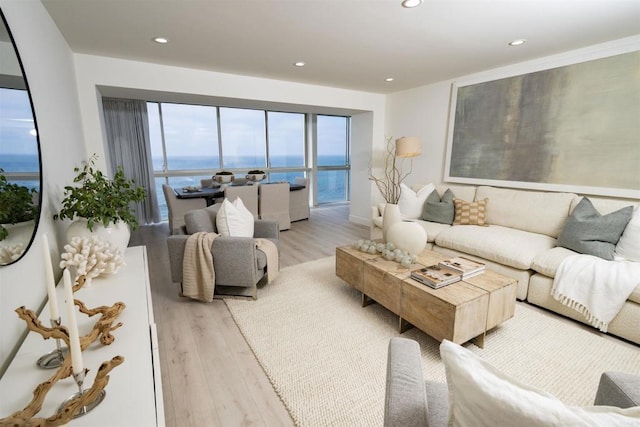 living area featuring light wood finished floors, a water view, and recessed lighting