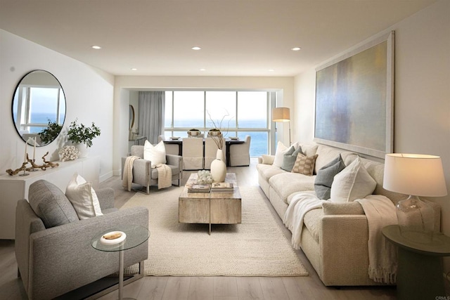 living area with wood finished floors, a water view, and recessed lighting