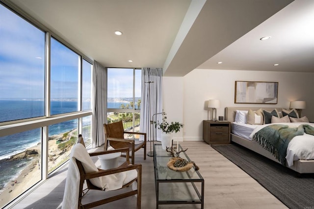 bedroom with floor to ceiling windows, a water view, recessed lighting, wood finished floors, and baseboards