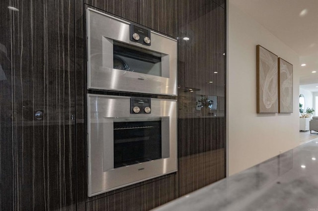 detailed view of modern cabinets, dark brown cabinets, recessed lighting, and stainless steel double oven