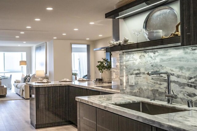 kitchen featuring a sink, recessed lighting, modern cabinets, light stone counters, and light wood-style floors