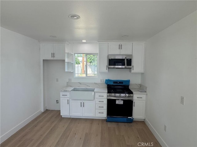 kitchen with stainless steel appliances, light wood-style floors, and white cabinets