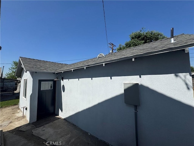 exterior view of stucco siding, a shingled roof, and fence