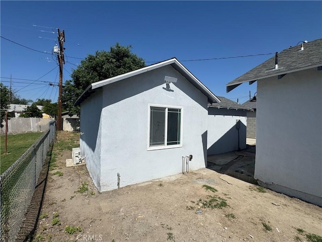 back of property featuring stucco siding and fence