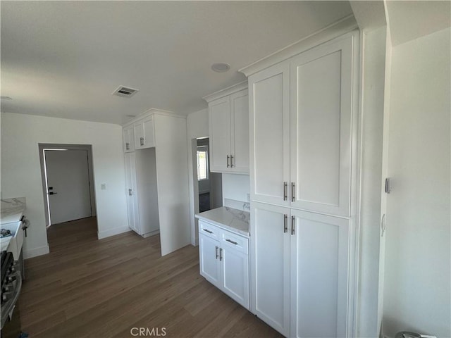 kitchen featuring white cabinetry, wood finished floors, baseboards, and light stone counters