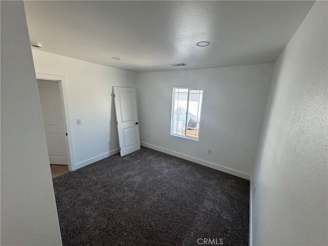 spare room with dark colored carpet and baseboards