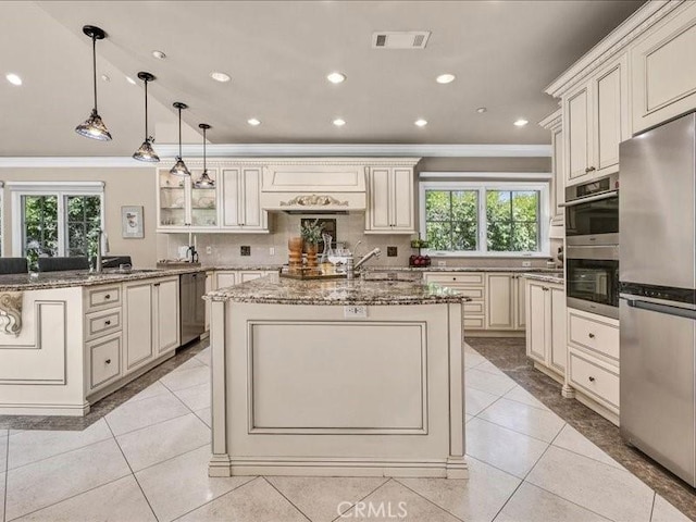 2560 Raleigh Dr, San Marino, CA 91108 - kitchen with cream cabinets, ornamental molding, appliances with stainless steel finishes, an island with sink, and light stone counters