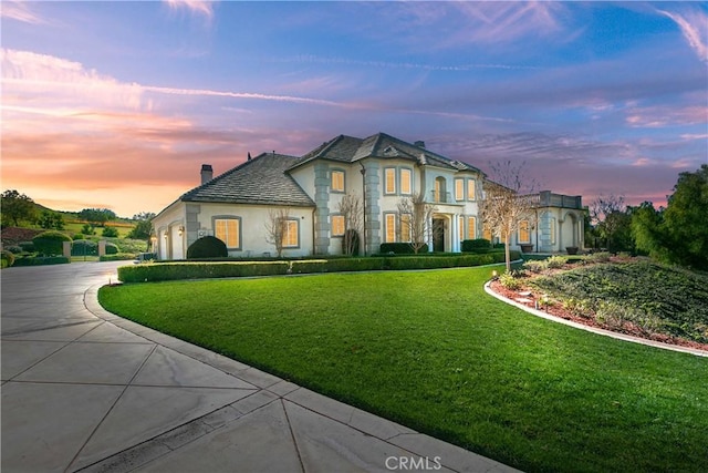 7280 Brandon Ct, Riverside, CA 92506 - french country inspired facade with curved driveway, stucco siding, a chimney, and a lawn