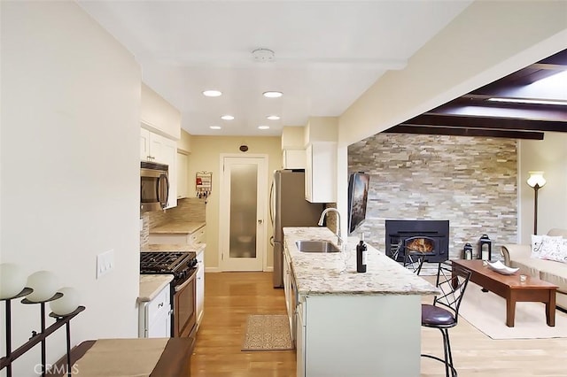 7391 Margerum Ave, San Diego, CA 92120 - kitchen with appliances with stainless steel finishes, a sink, a kitchen breakfast bar, white cabinetry, and light wood-style flooring