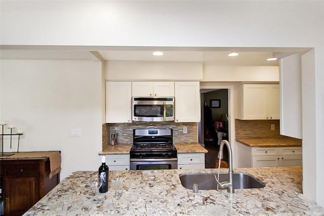 7391 Margerum Ave, San Diego, CA 92120 - kitchen with appliances with stainless steel finishes, a sink, decorative backsplash, light stone countertops, and recessed lighting