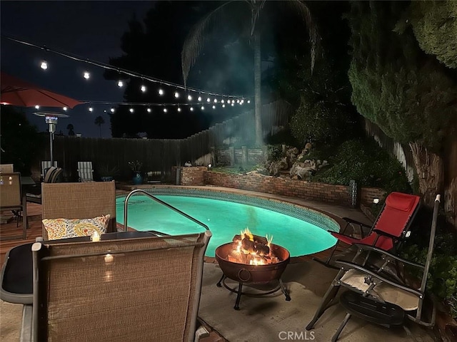 7391 Margerum Ave, San Diego, CA 92120 - pool at night with a fire pit, a fenced backyard, and a patio