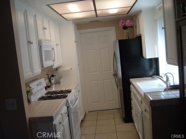 2452 Chandler Ave Unit 1, Simi Valley, CA 93065 - kitchen with white appliances, tile countertops, light tile patterned floors, and white cabinets