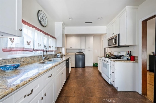 kitchen with white gas range oven, stainless steel microwave, dishwashing machine, white cabinets, and a sink