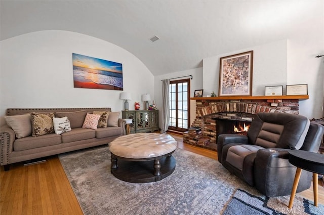 living area with lofted ceiling, wood finished floors, and a fireplace