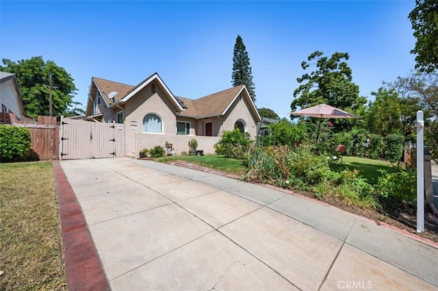 single story home with a gate, driveway, stucco siding, and a front yard