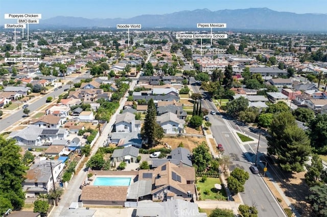 aerial overview of property's location featuring a mountainous background, nearby suburban area, and a pool area