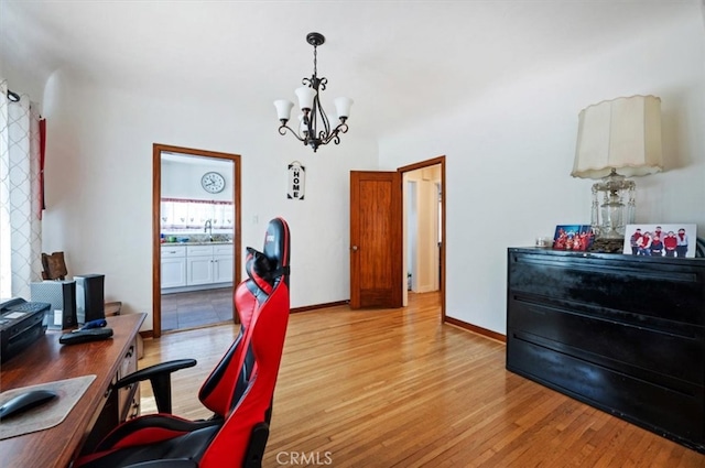 home office featuring light wood-type flooring, a chandelier, a sink, and baseboards