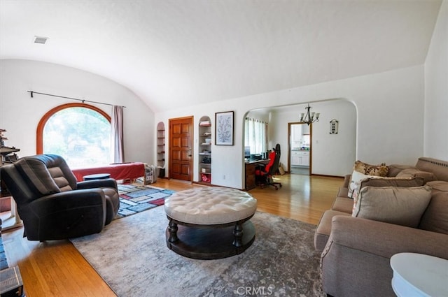 living room with wood finished floors, lofted ceiling, arched walkways, and built in features