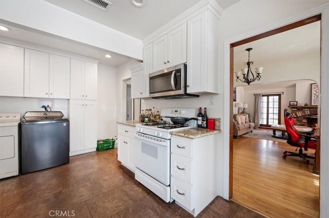 kitchen featuring gas range gas stove, stainless steel microwave, washing machine and dryer, white cabinetry, and recessed lighting