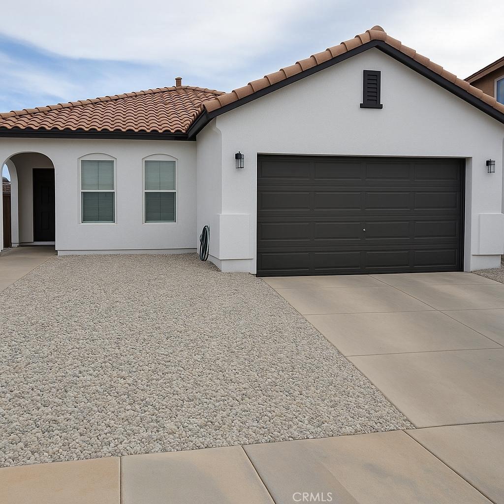 9422 Dragon Tree Dr, Hesperia, CA 92344 - mediterranean / spanish home featuring a tiled roof, an attached garage, stucco siding, and concrete driveway