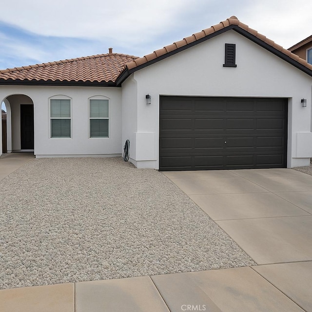 9422 Dragon Tree Dr, Hesperia, CA 92344 - mediterranean / spanish home featuring a tiled roof, an attached garage, stucco siding, and concrete driveway