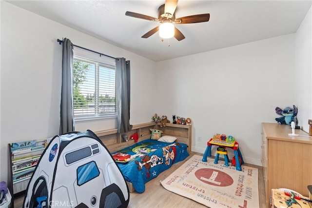 bedroom featuring wood finished floors, a ceiling fan, and baseboards