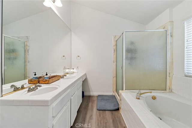 full bath featuring lofted ceiling, wood finished floors, a shower stall, a bath, and double vanity