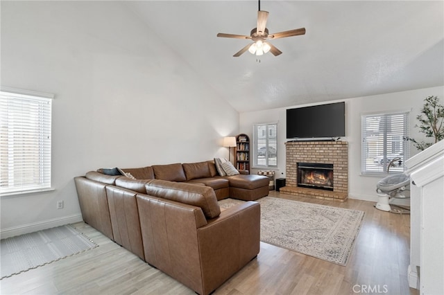 living room with a ceiling fan, high vaulted ceiling, a brick fireplace, light wood-style flooring, and baseboards