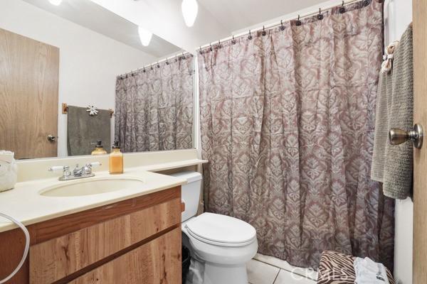 3805 Eisenhower Dr, Lake Elsinore, CA 92530 - full bathroom with tile patterned floors, vanity, toilet, and curtained shower