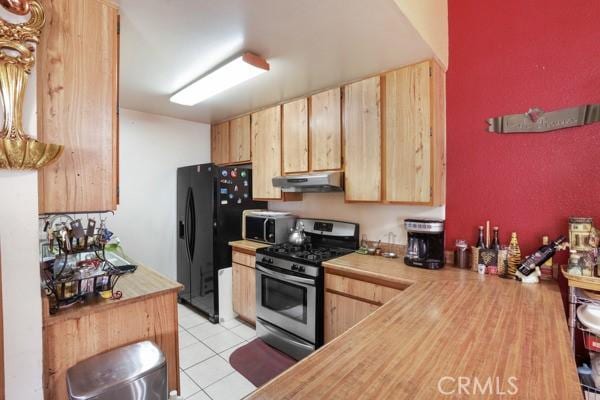 3805 Eisenhower Dr, Lake Elsinore, CA 92530 - kitchen with stainless steel appliances, under cabinet range hood, light brown cabinets, wood counters, and light tile patterned flooring
