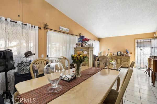 3805 Eisenhower Dr, Lake Elsinore, CA 92530 - dining room featuring vaulted ceiling, healthy amount of natural light, light tile patterned floors, and a textured ceiling