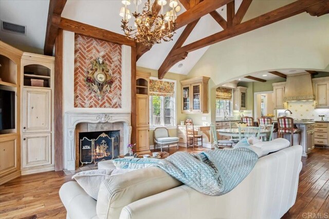 16056 Avenida Calma, Rancho Santa Fe, CA 92091 - living room featuring beamed ceiling, a chandelier, wood finished floors, arched walkways, and a fireplace