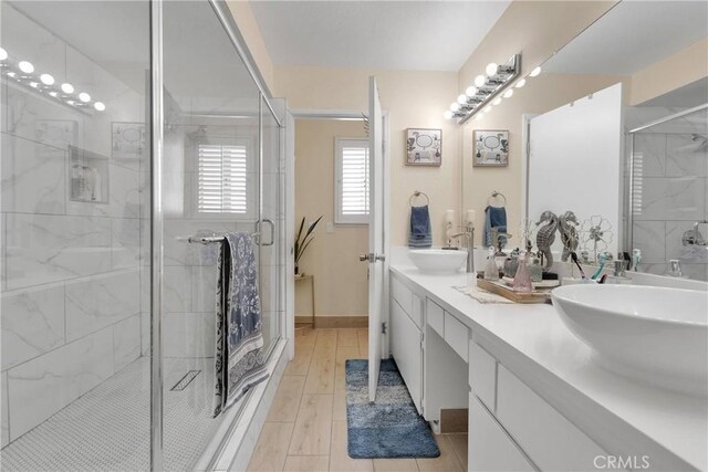 18060 Pebble Beach Dr, Victorville, CA 92395 - full bathroom featuring a stall shower, double vanity, and baseboards