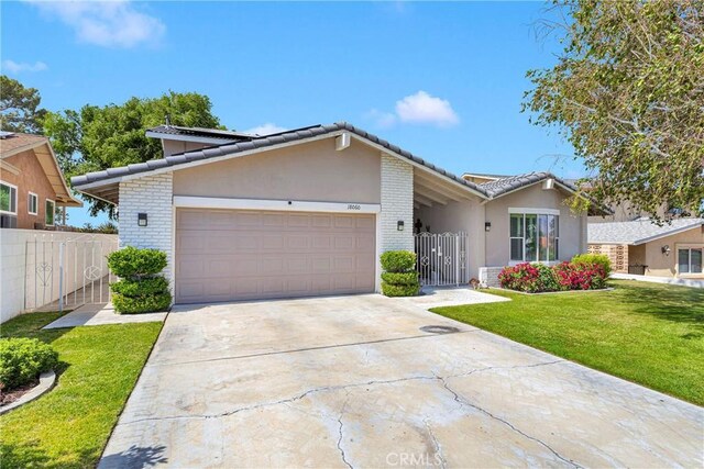 18060 Pebble Beach Dr, Victorville, CA 92395 - view of front facade with brick siding, a garage, driveway, a tile roof, and a gate