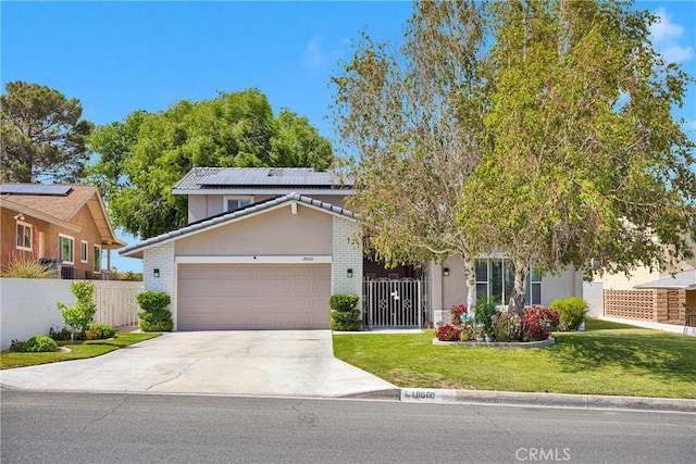 18060 Pebble Beach Dr, Victorville, CA 92395 - view of front facade with a garage, concrete driveway, roof mounted solar panels, stucco siding, and brick siding