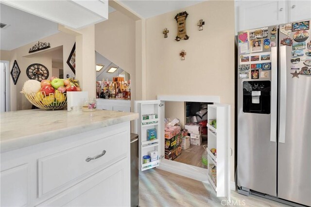 18060 Pebble Beach Dr, Victorville, CA 92395 - kitchen featuring stainless steel fridge, light wood-style floors, light stone countertops, and white cabinets