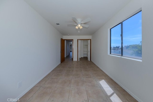 spare room with a ceiling fan, light tile patterned floors, and baseboards