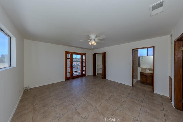 spare room with healthy amount of natural light, ceiling fan, a sink, and light tile patterned floors