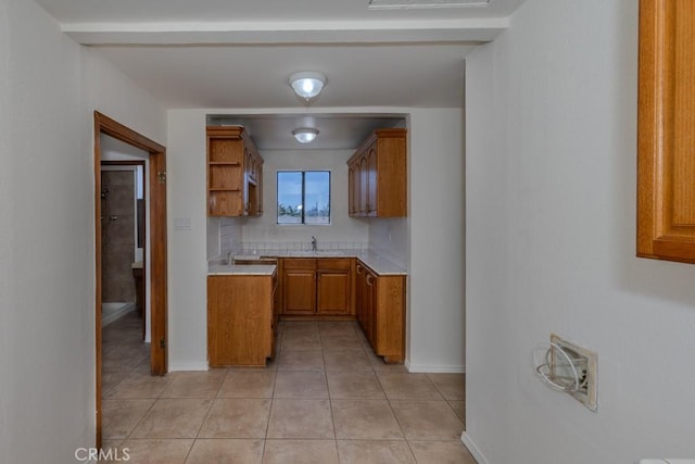 kitchen with brown cabinetry, light countertops, light tile patterned floors, baseboards, and open shelves