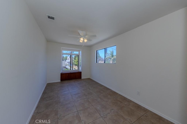 spare room featuring ceiling fan, baseboards, and light tile patterned floors