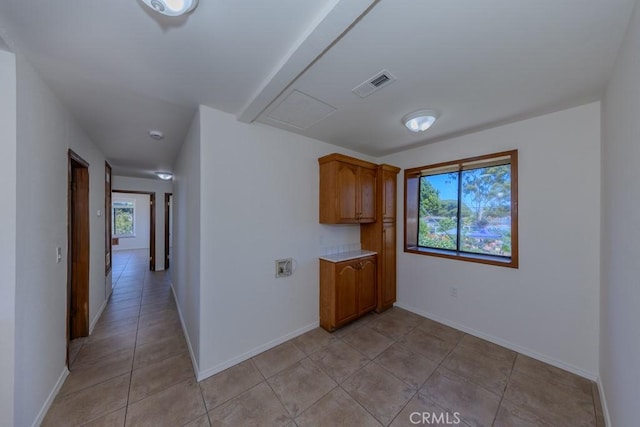 kitchen with light countertops, baseboards, brown cabinetry, and light tile patterned floors