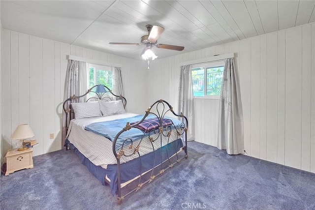 771 Woodland Rd, Crestline, CA 92325 - carpeted bedroom featuring multiple windows, wood walls, and a ceiling fan