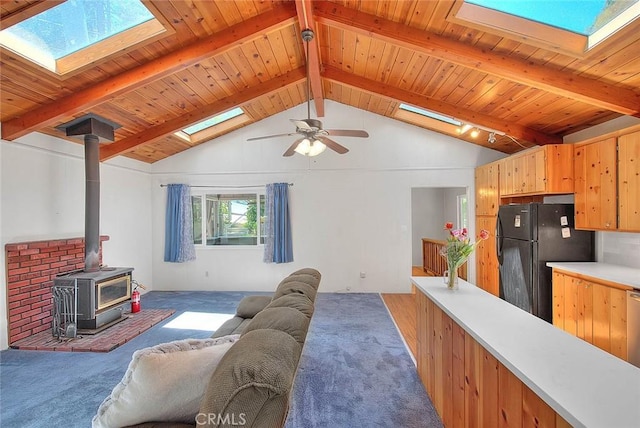771 Woodland Rd, Crestline, CA 92325 - carpeted living area featuring a skylight, a wood stove, wood ceiling, and a ceiling fan