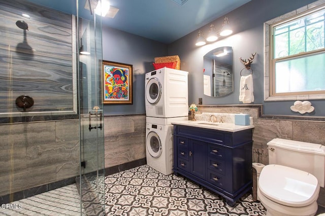 11 N San Gabriel Canyon Rd, Azusa, CA 91702 - bathroom featuring tile walls, stacked washer / dryer, a shower stall, a wainscoted wall, and toilet