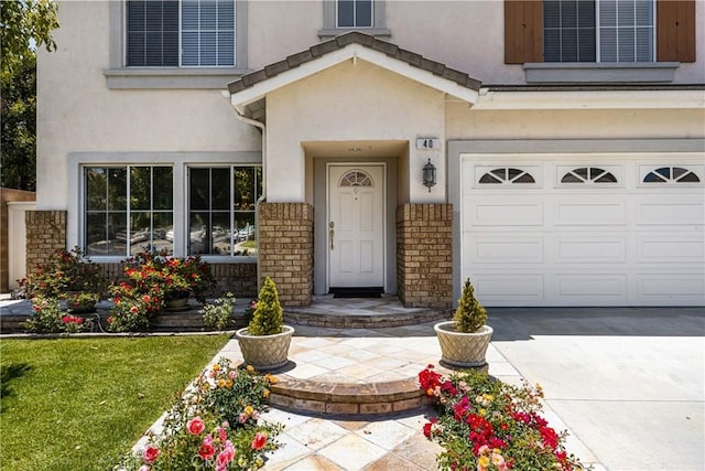 40 Calais, Irvine, CA 92602 - view of exterior entry featuring a garage, stucco siding, brick siding, and concrete driveway