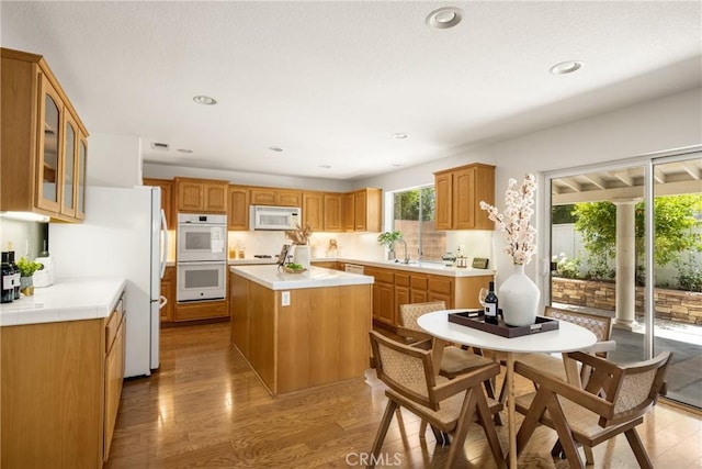 40 Calais, Irvine, CA 92602 - kitchen featuring white appliances, a center island, glass insert cabinets, light wood-style floors, and a sink