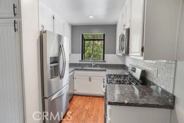27929 Tyler Ln Unit 744, Canyon Country, CA 91387 - kitchen featuring stainless steel appliances, a sink, decorative backsplash, white cabinets, and light wood-style flooring