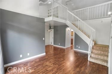 27929 Tyler Ln Unit 744, Canyon Country, CA 91387 - unfurnished living room featuring stairway, a high ceiling, baseboards, and wood finished floors